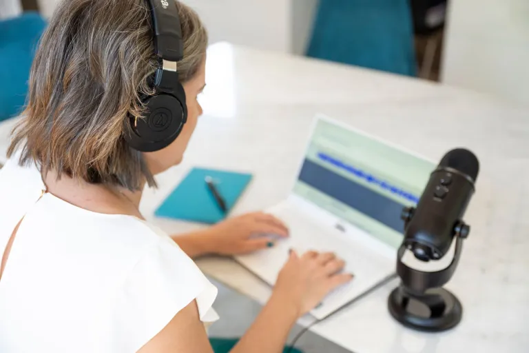 Laura McRae editing a podcast on her laptop sitting at a dining table