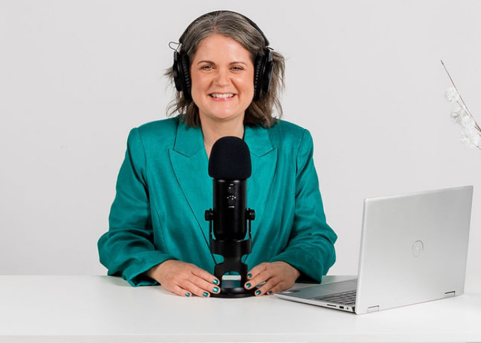 Laura McRae Podcast Consultant siting at a desk recording a podcast episode