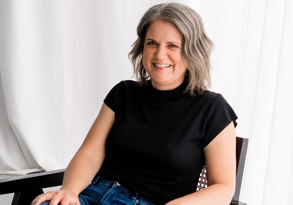 Laura McRae sitting on chair wearing a black t-shirt
