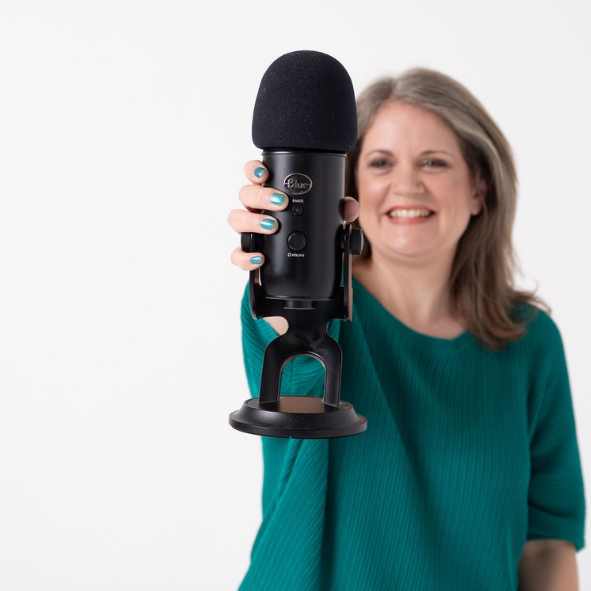 Laura McRae holding a Blue Yeti microphone close to the camera